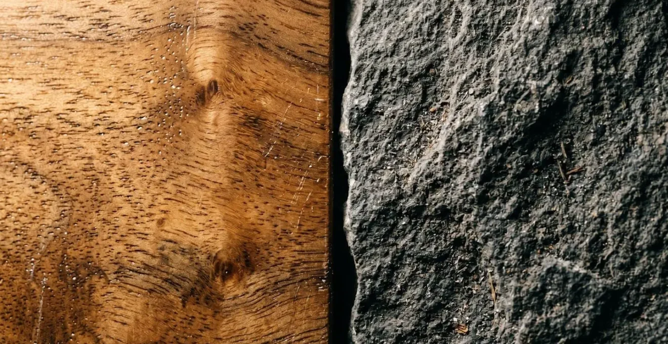Gros plan sur des textures de bois précieux et de pierre naturelle côte à côte, illustrant leur incompatibilité environnementale.